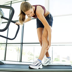 woman on treadmill holding leg